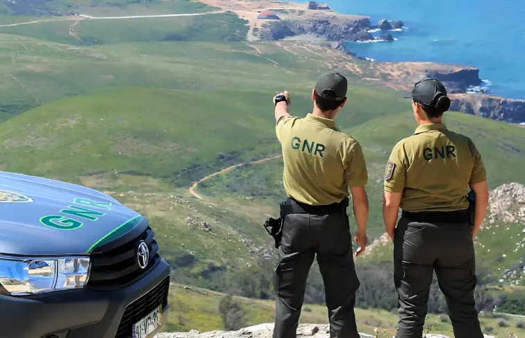 Dois oficiais da GNR a apontar para montanhas e floresta